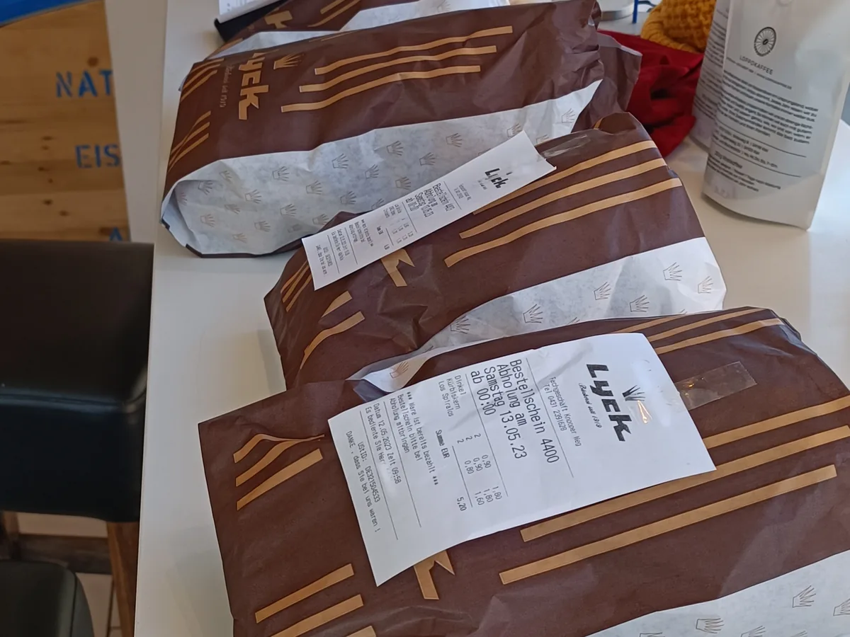 Gepackte Bestellungen in Lyck-Tüten mit Bestellscheinen auf der Theke.