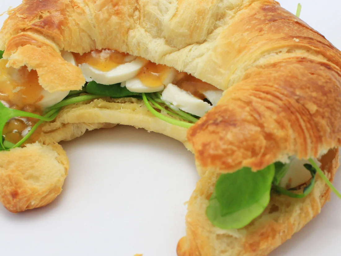 Ein aufgeschnittenes Croissant mit Ziegenkäse und Pfirsich.