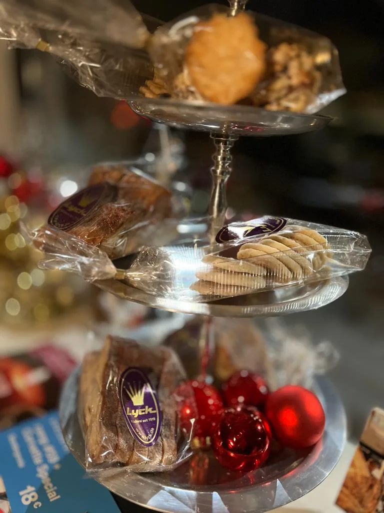 Eine Etagere mit Weihnachtsgebäck in Tüten, davor rote Christbaumkugeln.